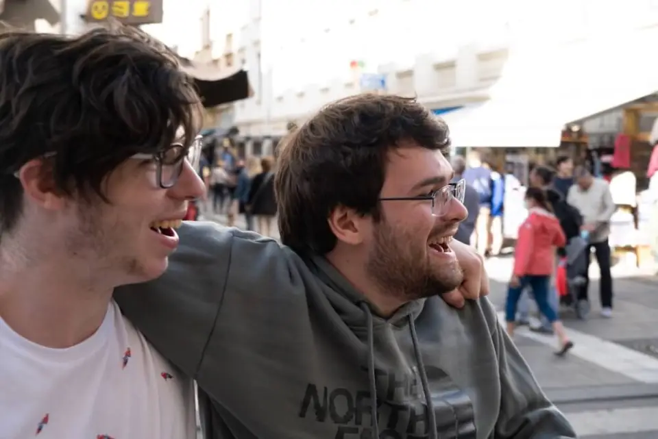 Two WanderRock travelers laughing together on a street in Europe