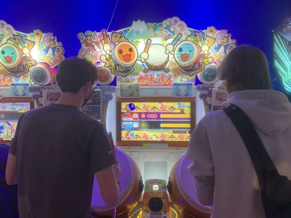 Two WanderRock travelers playing taiko drums in a Japanese arcade